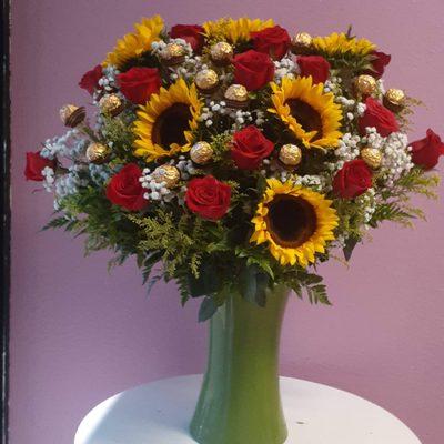 arreglo de rosas y girasoles en base de vidrio con chocolates ferrero rocher