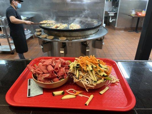 Bring your tray to the guy so he can cook your food on the grill.