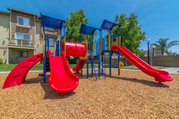 Playground with mulch, grass, and benches.