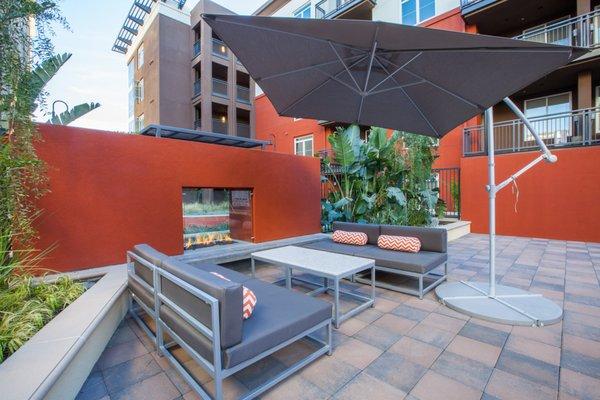 Outdoor fireplace with lounge seating and shade.