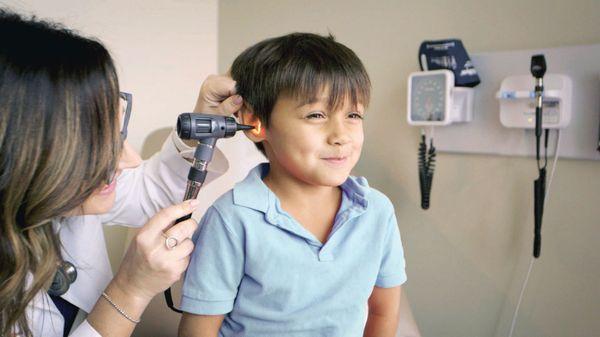 Summer Carlson examining a young boy's ear canal.