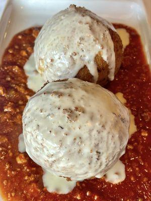 Stuffed rice balls with beef Bolognese over marinara sauce smothered with Alfredo sauce