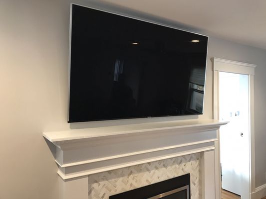 75" TV mounted above fireplace w/ wiring concealed