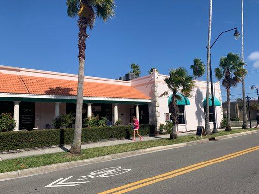 The front door is located behind the person in the pink shirt.