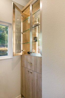 a closer look at the custom built-in with lower storage that matches the vanity and brushed steel framed glass doors on top.