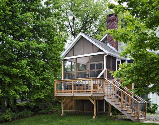 Screened porch with gable roof and deck with stairs to yard.