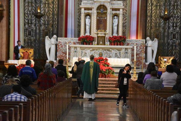 A priest walks down the center isle towards the altar.