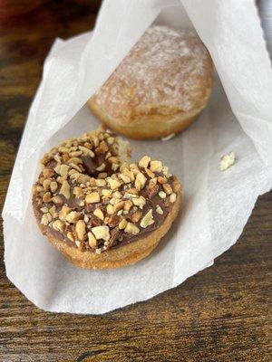 two donuts. one has chocolate and peanuts, and the other has powdered sugar and a lemon jelly filling