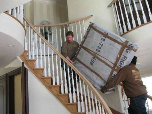 Moving Right Along movers bringing a large piece of furniture up a flight of stairs