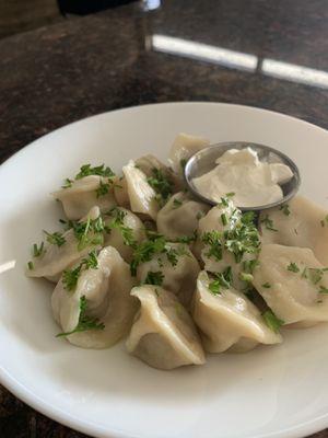 Traditional Eastern European dumplings (pelmeni) with savory meat filling, served with rich sour cream--a hearty and flavorful classic!