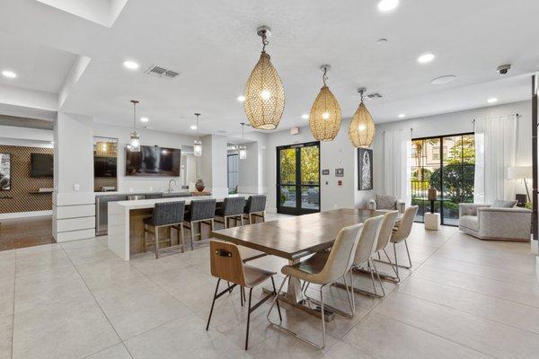 Game room with modern furniture, hanging light fixtures, and wall-mounted TVs at Lantower Grande Flats Apartments.