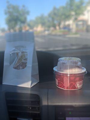 Waffle pieces in a white bag, cheesecake ice cream with strawberries mixed in a Cold Stone cup with a lid