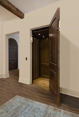 Plantation series residential elevator with wood paneled accordion gates on adjacent openings.