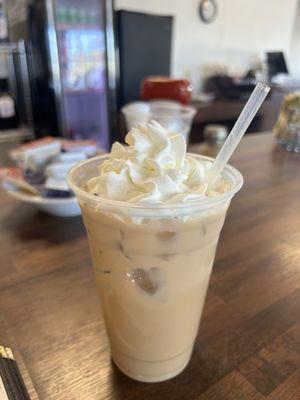 Caramel and hazelnut iced latte with whipped cream.