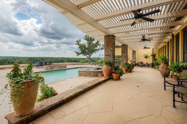 Enjoy cover and cooling fans with lounging poolside on the hilltop ranch for sale in Gilmer TX.