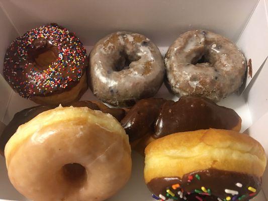 Chocolate sprinkle donut, blueberry cake donut, chocolate twist, glazed donut, and another chocolate with sprinkles.