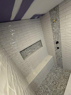 Pebble floor with vertical accent, hidden drain, and custom niche.