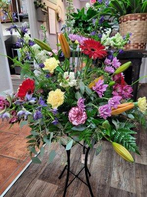 Lily's, gerbera daisy's, roses, delphinium, arranged in bird bath. The family will have something to place in their garden.