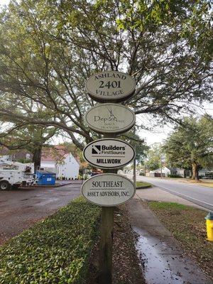 (Directional Signage): A multi-business signpost at 2401 Ashland Village, featuring a sign for Builders FirstSource Millwork....