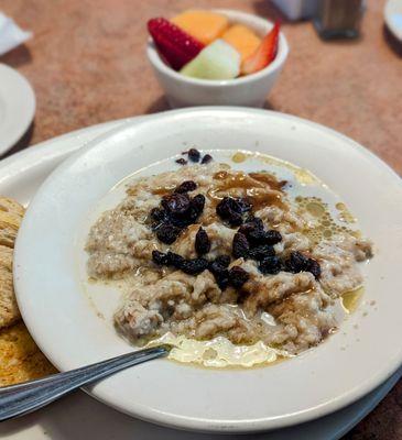 Creamy oatmeal loaded with butter, brown sugar, raisins and milk, plus fresh fruit and sourdough toast.