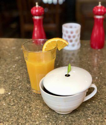 Freshly squeezed orange juice alongside hot tea.