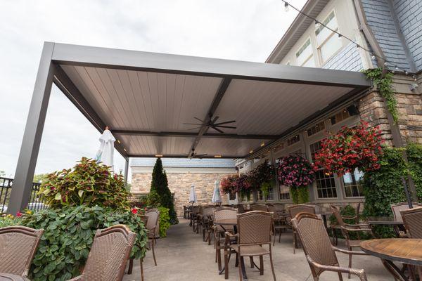 An aluminum pergola covers a restaurant patio with the louvers in the closed position.