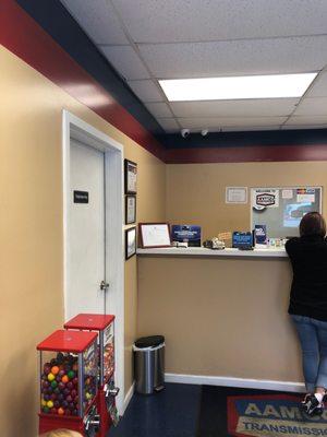 Inside front desk and lobby area of repair shop. The customer at counter waits to be acknowledged.