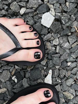 One left foot with half the right foot showing. Black nail polish with two silver stars on each big toe.