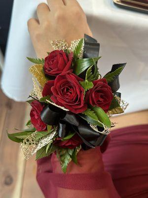 Corsage - Burgundy Rose to match both of their clothes. Gold to matches with her jewelry and Black ribbon matches her dates black shirt.