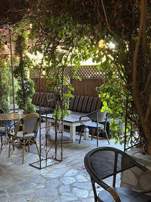 The outdoor seating area which is completely covered by foliage.