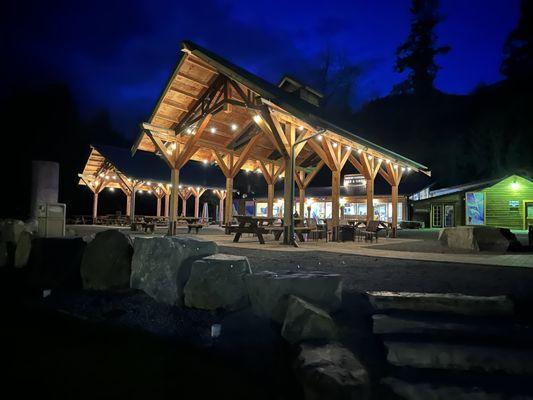 Outdoor covered structures with a big gas firepit and multiple firepit tables.