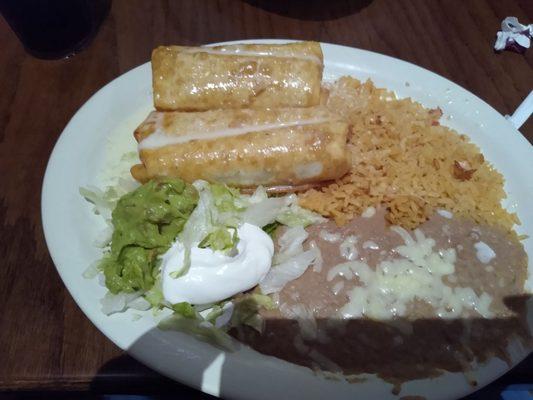 Shredded beef chimichangas with cheese sauce, rice, refried beans with cheese.