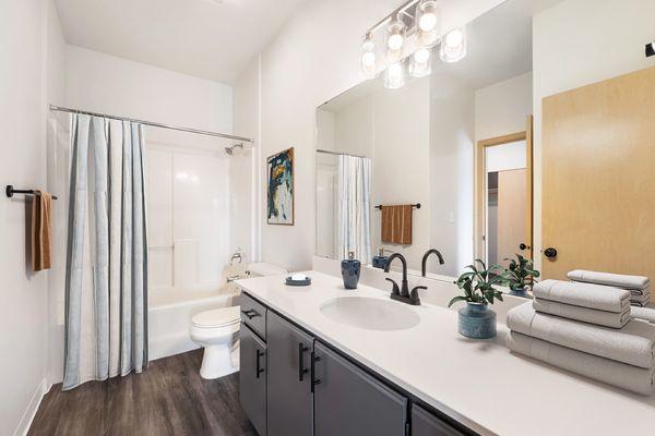 Shoreline Village Apartments in Richland, WA - Newly renovated bathroom with gray cabinets, faux wood flooring and full bath/shower,