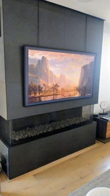 Samsung frame TV suspended with cables to prevent damage to tile fireplace.