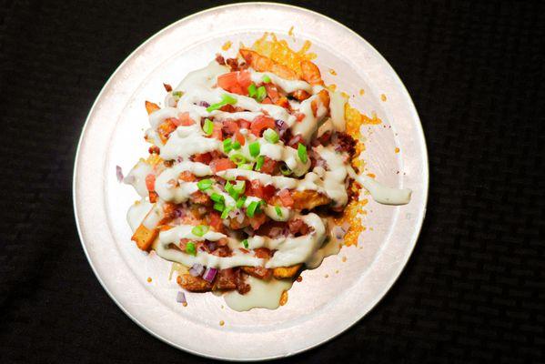 Garbage Fries- Fries tossed in Siracha seasoning & Garlic Salt then loaded with Bacon, Red Onions, Jalepenos, Tomatoes, Ranch & Queso.