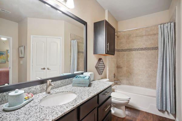 Primary bathroom with framed mirror, granite countertops, and garden tub