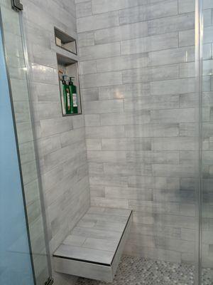 Floating bench, tile up to the ceiling. Shower glass door