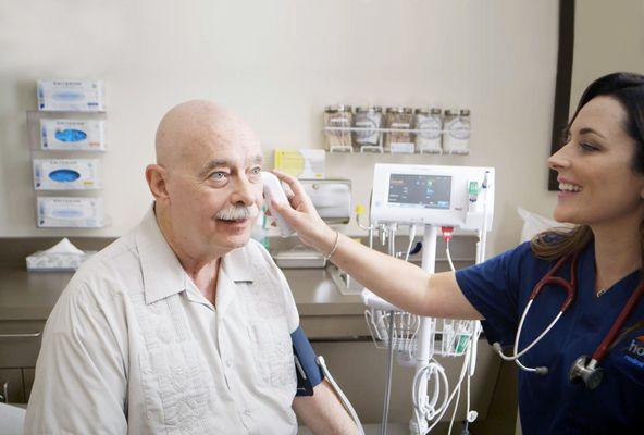 Summer Carlson taking the temperature of a patient.