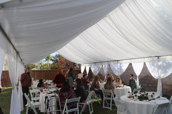 Tent with draping, white padded resin chairs & tables