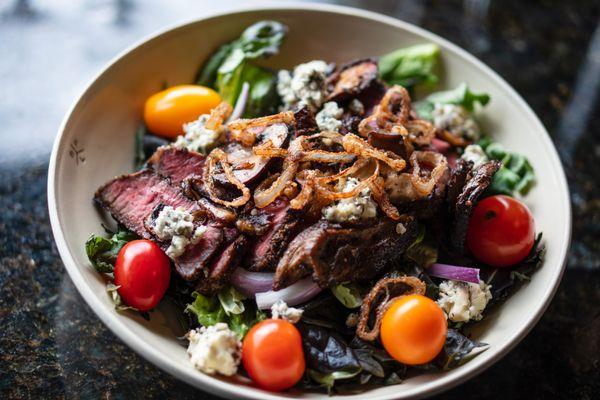 Steak Your Claim Salad: Wagyu Flat Iron steak on gourmet mixed greens. Smoked wild mushrooms, Fourme d'Ambert Bleu Cheese, fried shallots.