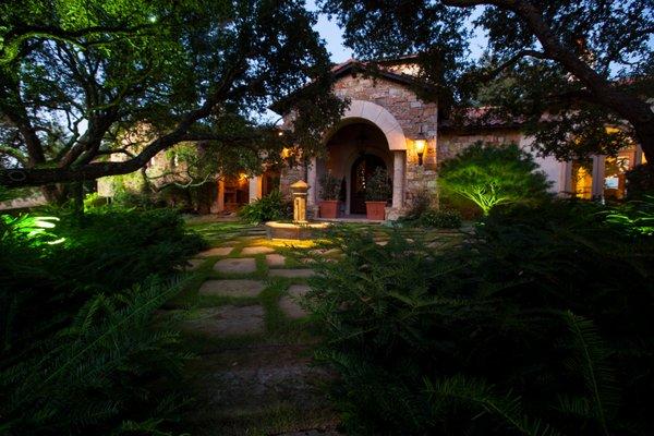 Uplights on the house, trees, and landscaping bring the house to life at night.