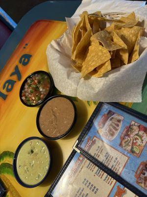 Chips with sides of pico de gallo, refried beans and a pico mix with sour cream.