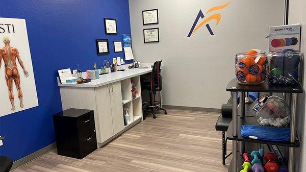 An interior view of the recovery room at Airrosti Brownsville. Weights, lacrosse balls, and resistance bands are visible in the background.