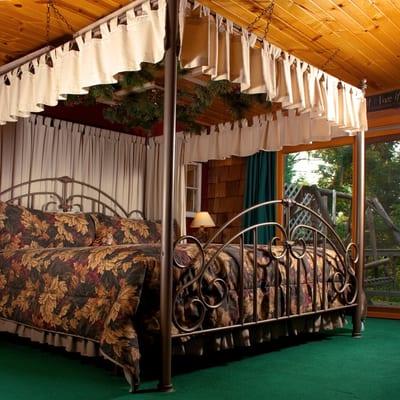 A rustic canopy bed has patio doors out to your private deck in the Dreamcatcher Suite.