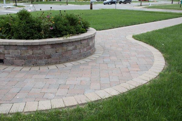 curved pathway with pavers around a raised flower bed