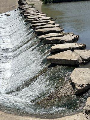 Waterfall on Trinity River wit stone walkway crossing the river and connecting two sections of the trail