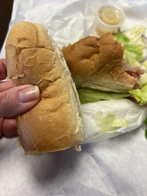 Italian sub being held for size scale=cheap hot dog bun