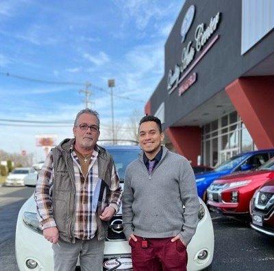 Julian the salesman, and the purchaser standing in front of the newly purchased car.