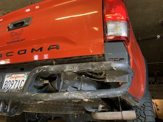 Damaged rear metal bumper, tailgate, and taillight due to accident