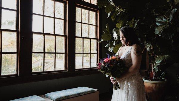 Picture of bride Samantha wearing her dress from Aurora Bridal, and her Bouquet from Buds Etc, inside the bridal suite at Rockledge Gardens